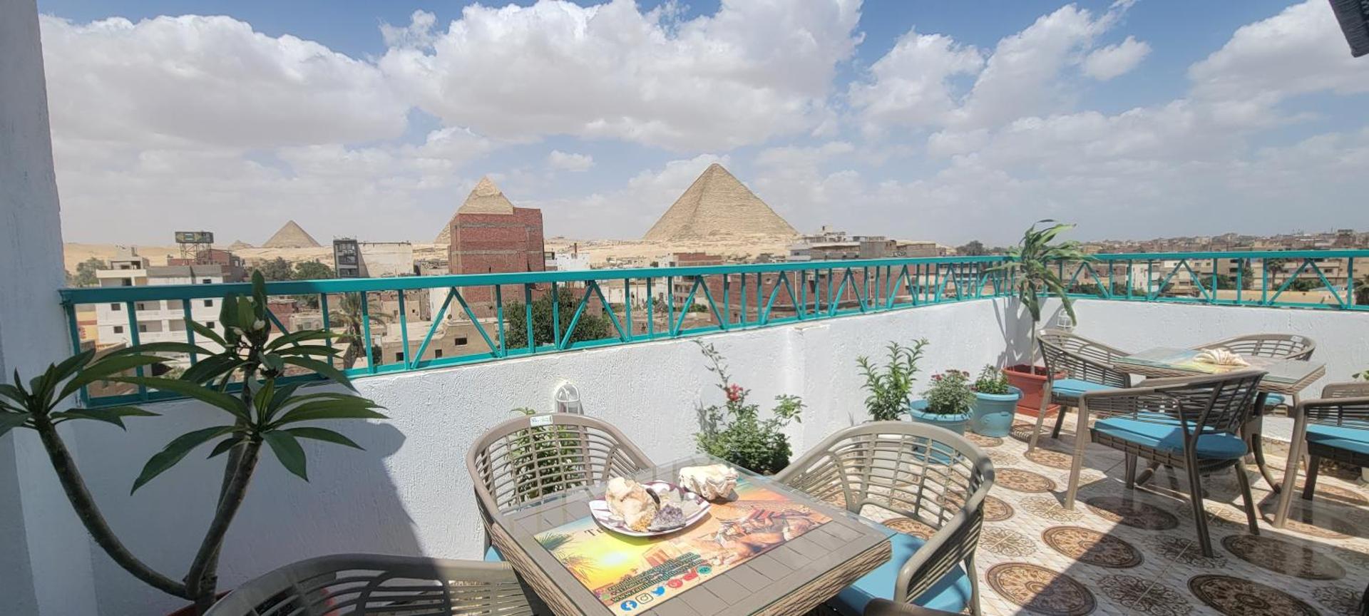 Rooftop tables with the pyramids under a cloudy sky