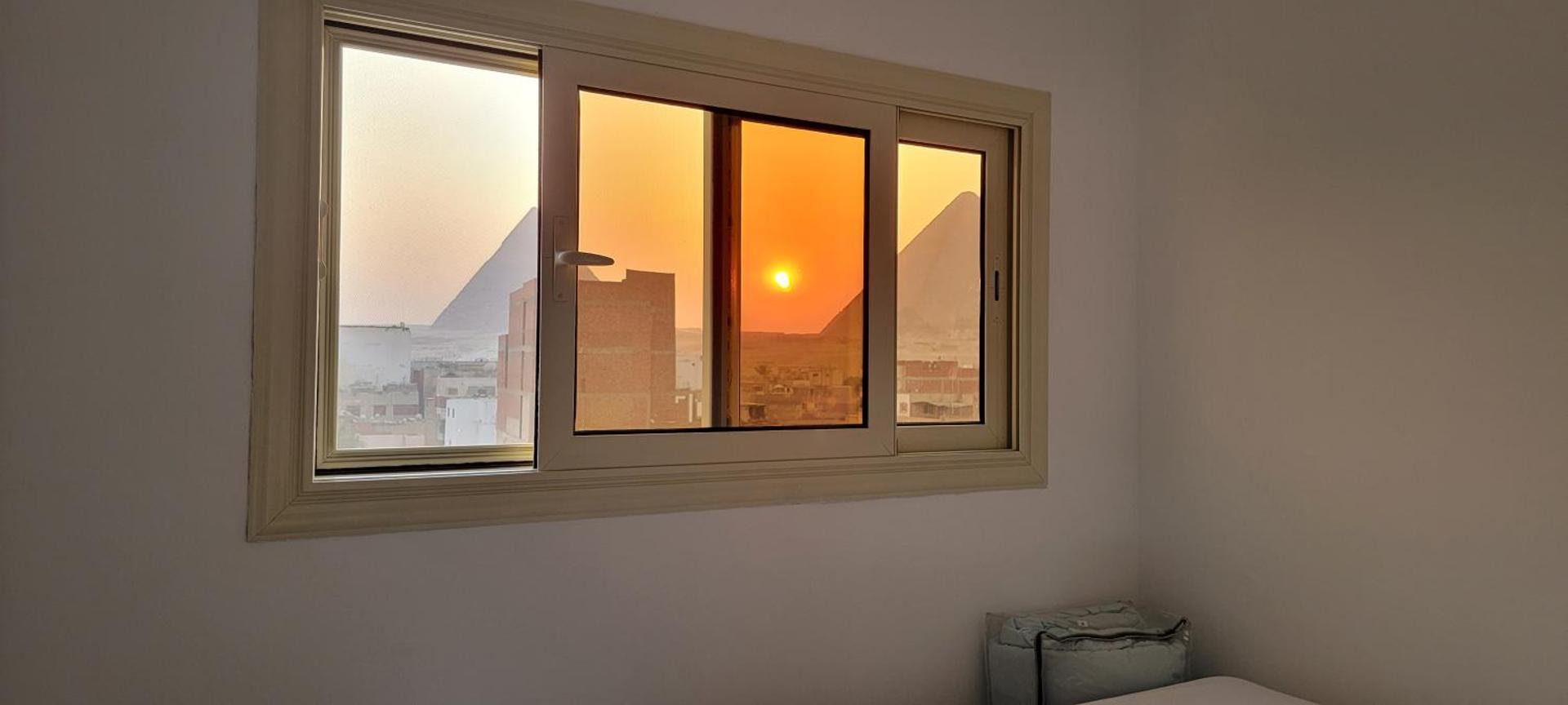 The pyramids at sunset, framed by a guest room window